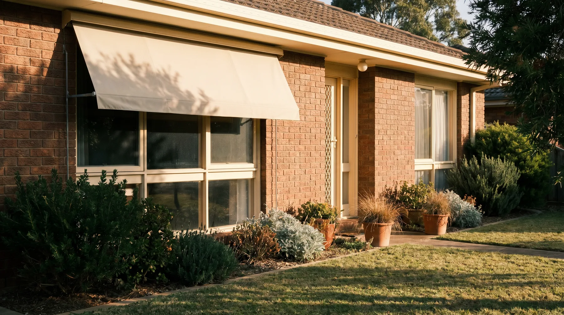 A canvas awning shading a brick home's west window